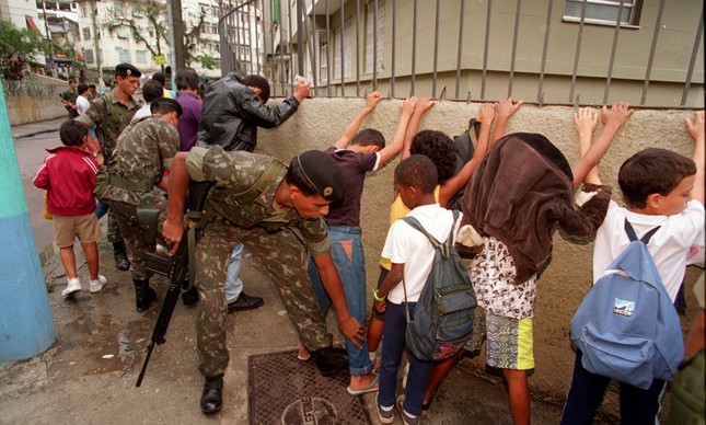 Foto de militares revistando crianças em porta de escola tem 22 anos